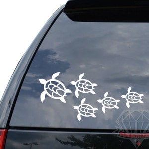 May include: White vinyl decal of a family of five sea turtles, with the largest turtle at the top and the smallest at the bottom, on a black car window.