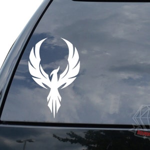 May include: White vinyl decal of a stylized phoenix with its wings spread. The phoenix is facing forward with its head tilted up.