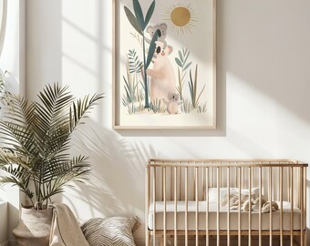 以下が含まれることがあります： 森の背景に3匹の コアラを描いた額縁付きのイラスト。コアラは薄いピンクとグレーの色合いで描かれており、背景には太陽が輝いています。イラストは白い壁に飾られており、手前に木製のベビーベッドと鉢植えの植物があります。