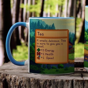 May include: Two white mugs with blue handles. Both mugs feature a green and brown illustration of a forest scene with a text box that reads "Tea" and lists the benefits of drinking tea. The text box reads "It smells delicious. This is sure to give you a boost. +3 Energy +1 Health +1 Speed".
