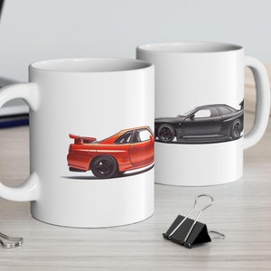 Może przedstawiać: Dwa białe ceramiczne kubki z wzorem czarnego i czerwonego samochodu. Kubek po lewej stronie ma czerwony samochód z czarnym paskiem, a kubek po prawej stronie ma czarny samochód z czerwonym paskiem.