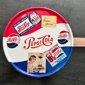 May include: Vintage Pepsi-Cola serving tray with a red, white, and blue color scheme. The tray features various Pepsi-Cola advertisements from the 1930s, 1940s, and 1950s, including the text "Say 'Pepsi, please!'".