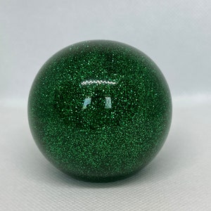 May include: A green glitter ball with a smooth, shiny surface.