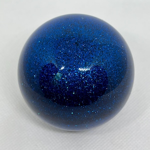 Peut inclure: Une boule de paillettes bleues avec un centre bleu foncé. La boule est ronde et a une surface lisse.