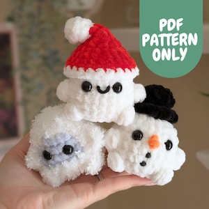 Può includere: Tre giocattoli di peluche all'uncinetto: un pupazzo di neve con un cappello a cilindro nero, un fantasma bianco con un cappello di Babbo Natale rosso e uno yeti bianco con gli occhi neri.  MODELLO PDF SOLO.