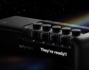 May include: A black device with five clear bottles, each capped with a black lid. The text "eufy Make" and "They're ready!!" are illuminated in white. A rainbow-like light effect is visible.