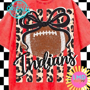 Könnte beinhalten: Ein rot mineralgewaschenes T-Shirt mit einer Grafik eines braunen Footballs mit weißen Schnürsenkeln, gekrönt von einer schwarzen Schleife. Das Design enthält einen Leopardenmuster-Hintergrund und das Wort "Indians" in schwarzer Schrift.