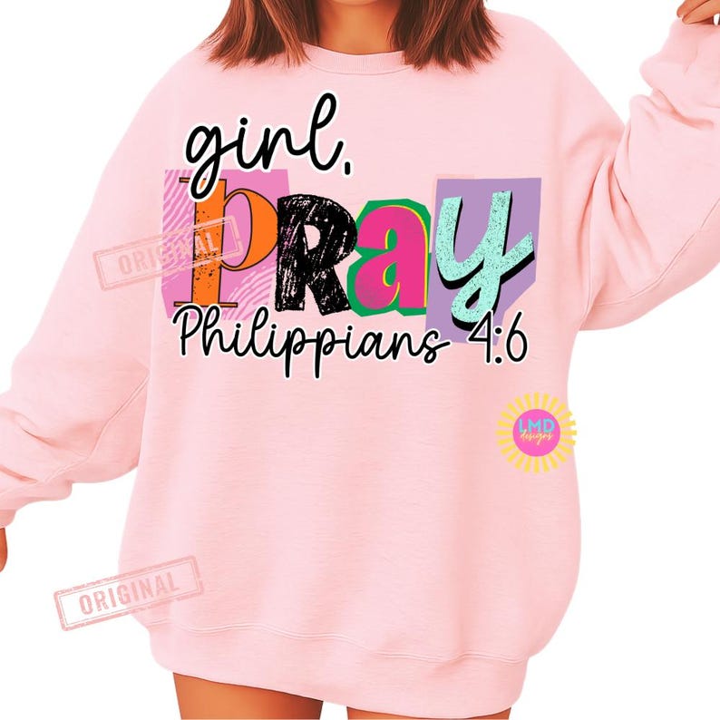 May include: A light pink sweatshirt with the words "girl. PRAY Philippians 4:6" in a colorful design. The word "PRAY" is in a black, orange, pink, and green block design. The sweatshirt has long sleeves.