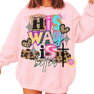 May include: A light pink sweatshirt with the text "His Way is better" in a collage style. The design includes a cross, hearts, and leopard print accents. The word "Original" is also visible.