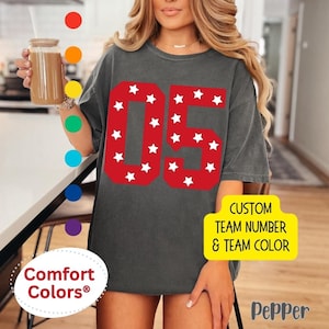 May include: A gray t-shirt with a red number "05" surrounded by white stars. The text "CUSTOM TEAM NUMBER & TEAM COLOR" is on the bottom right corner of the shirt.