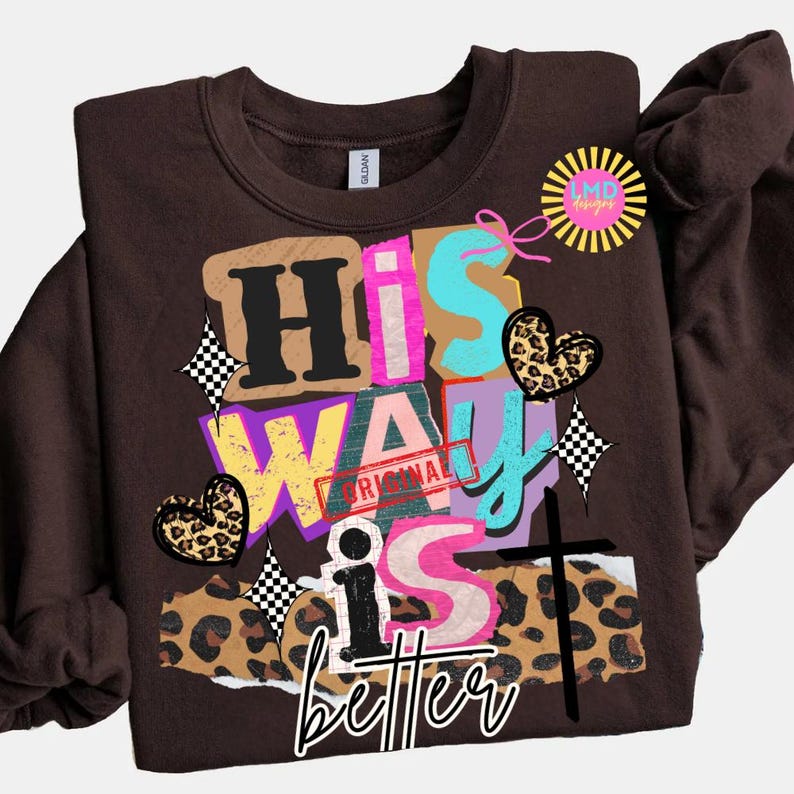 May include: A brown sweatshirt with the words "His Way Is Better" in a colorful, layered design. The design includes leopard print hearts, a cross, and the word "Original" stamped on the design.
