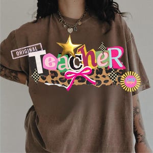 May include: A brown t-shirt with the word "Teacher" in a colorful, layered design. The design includes a gold star, a pink bow, and a leopard print section. The word "Original" is printed on a rectangular label.