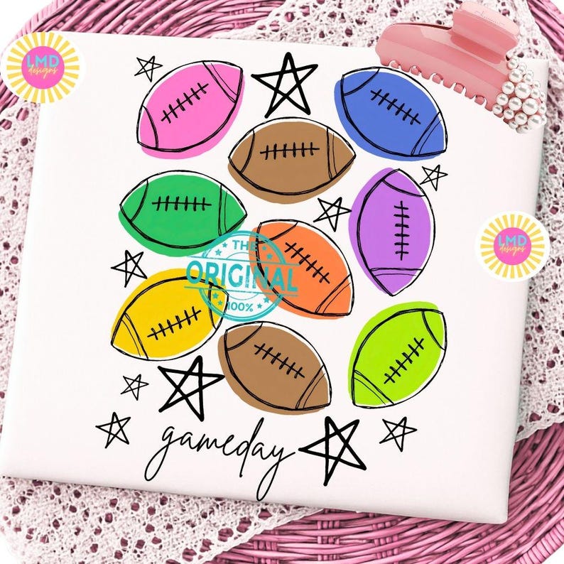 May include: A white surface featuring a colorful graphic print of multiple American footballs in pink, brown, green, blue, purple, orange, yellow, and lime green, interspersed with black hand-drawn stars and the word gameday in black script.