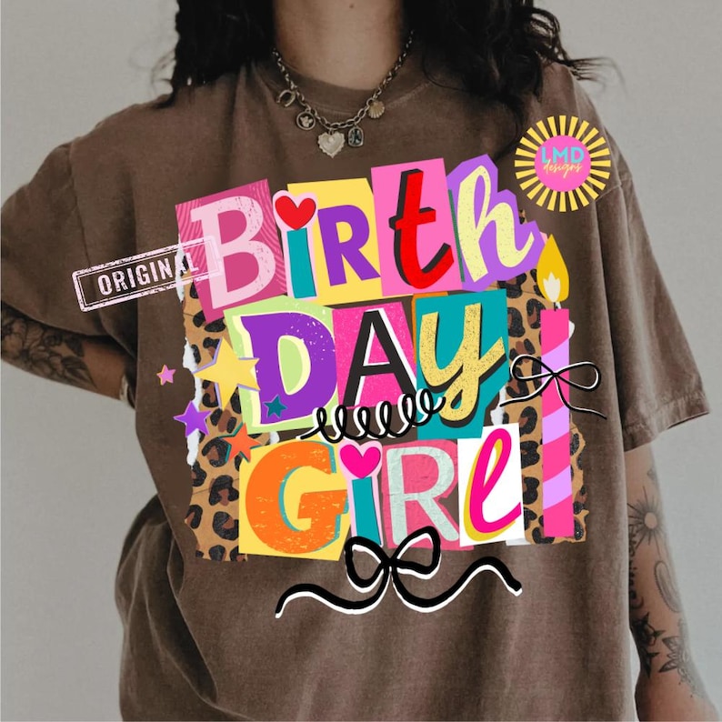 May include: Brown t-shirt with a colorful "Birthday Girl" graphic. The design features the words "Birthday Girl" in various colors, a leopard print background, stars, hearts, candles, and a bow.