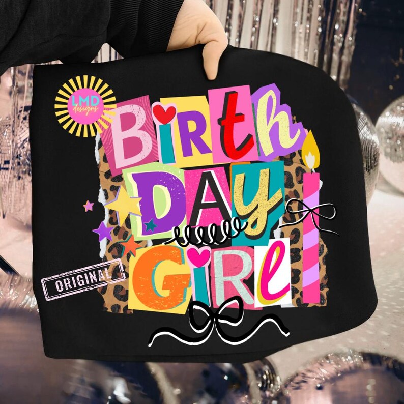 May include: Black tote bag with a colorful "Birthday Girl" design. The design includes the words "Birthday Girl" in various colors, stars, hearts, and a bow. The bag also has a "LMD designs" logo and the word "ORIGINAL".