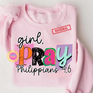 May include: A light pink sweatshirt with the words "girl. PRAY Philippians 4:6" in a colorful, layered design. The word "ORIGINAL" is stamped in red. A circular logo is on the left side of the sweatshirt.