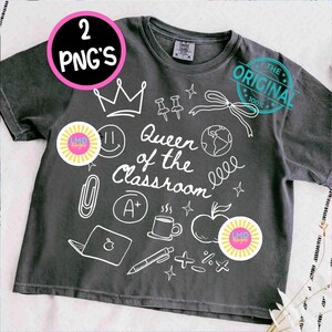 May include: Dark gray t-shirt with white graphic illustrations and the text "Queen of the Classroom." The design includes a crown, apple, coffee cup, and other school-related icons. A pink and yellow sticker is also visible.
