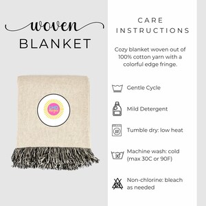 May include: A beige woven blanket with a black and white fringe. The blanket has a circular logo in the center with the text "LMD Designs". Care instructions are listed on the right side of the image, including instructions for gentle cycle washing, mild detergent, tumble dry on low heat, machine wash cold, and non-chlorine bleach as needed.