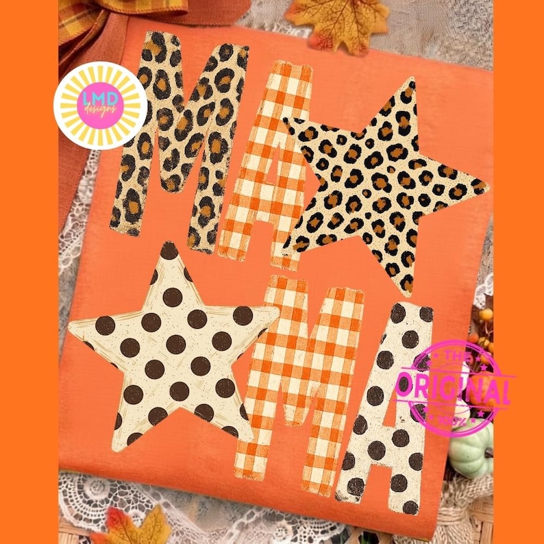 May include: An orange t-shirt featuring the word MAMA in a decorative font. The letters M and A are filled with leopard print and orange gingham patterns. Two stars are integrated into the design, one with leopard print and one with black polka dots.