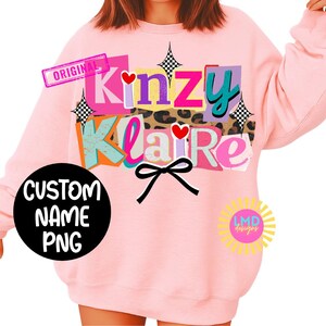 May include: Pink sweatshirt with the text "Kinzy Klaire" in a colorful, layered design. Features a black bow, hearts, and the words "Custom Name PNG" on a black circle. Includes a "Original" stamp.
