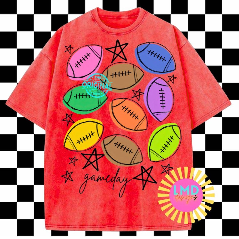 May include: A red mineral-wash t-shirt featuring a graphic print of multi-colored footballs in pink, blue, brown, green, orange, purple, and yellow. The design includes black hand-drawn stars and the word gameday in a cursive script font.