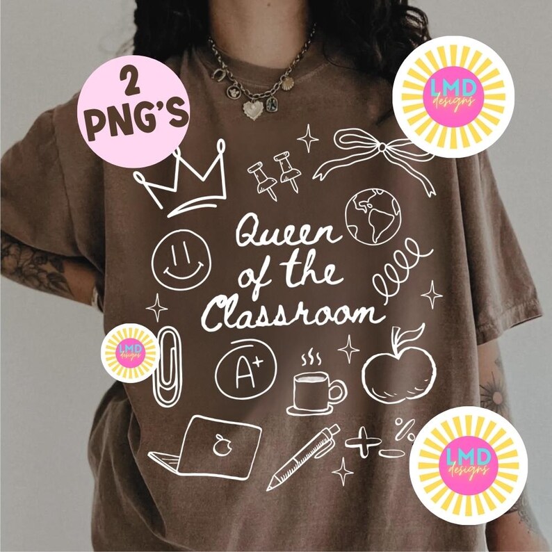 May include: A brown t-shirt with a white graphic design featuring the text "Queen of the Classroom" and various school-related icons such as a crown, apple, and pencil. The shirt also has two pink circles with the text "2 PNG's" and "LMD designs".