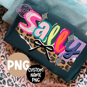 May include: Dark green t-shirt with the word "Sally" in a colorful, layered design. The design includes a leopard print, a black bow, and checkered starbursts. The shirt also has a "PNG" graphic and a "Custom Name PNG" graphic.