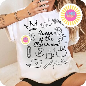 May include: White t-shirt with the phrase "Queen of the Classroom" and various black doodle illustrations, including a crown, apple, and coffee cup. The shirt has a round logo on the front.