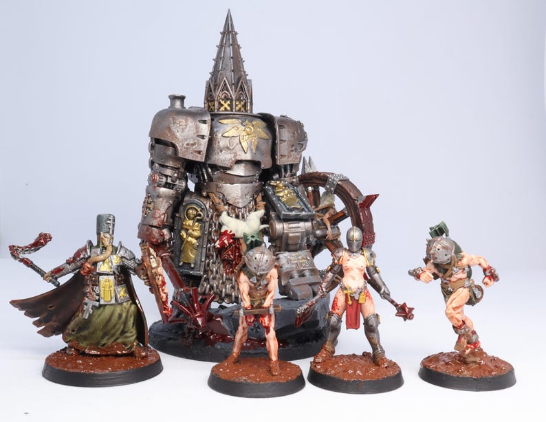 Puede incluir: Una colecci&oacute;n de figuras en miniatura, que incluye una figura grande y detallada con forma de robot y varias figuras de guerreros m&aacute;s peque&ntilde;as. Las figuras est&aacute;n pintadas con tonos met&aacute;licos y terrosos, y est&aacute;n colocadas sobre bases circulares marrones. El tema general sugiere un entorno de fantas&iacute;a o ciencia ficci&oacute;n.
