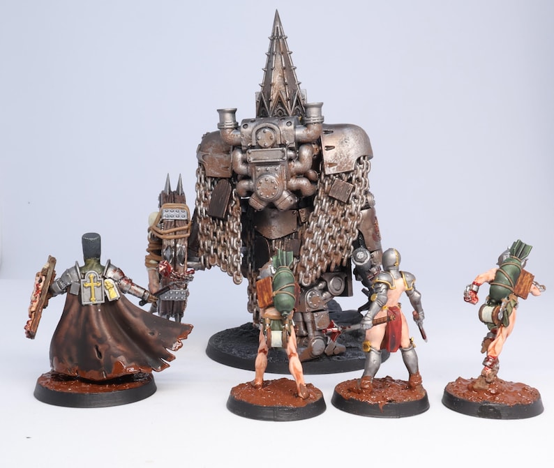 Puede incluir: Figuras en miniatura de personajes de fantas&iacute;a, incluyendo una figura grande, met&aacute;lica y mec&aacute;nica con una cabeza puntiaguda, y varias figuras m&aacute;s peque&ntilde;as con armaduras y capas. Las figuras est&aacute;n pintadas con texturas y colores detallados, sobre bases marrones.