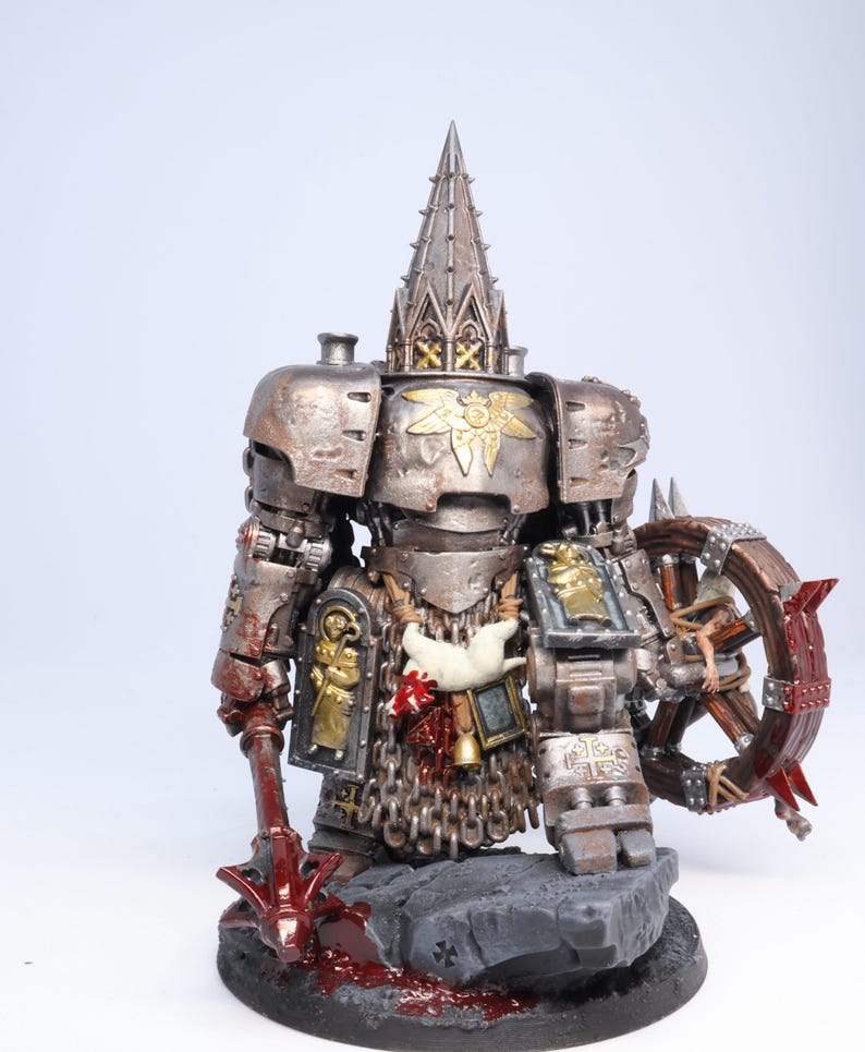 Puede incluir: Figura en miniatura detallada de un guerrero fuertemente blindado. La figura es principalmente met&aacute;lica con detalles dorados, un tocado alto y ornamentado y una rueda con p&uacute;as. La base es gris con detalles rojos, lo que sugiere una escena de batalla.