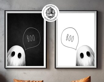 May include: Two framed Halloween art prints featuring a ghost saying "Boo" in a speech bubble. One print has a black background, the other white. The art hangs above an orange leather couch with matching pillows, pumpkins, and a coffee table.