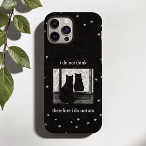 May include: A black phone case featuring a white star pattern and a central rectangular graphic of a black cat sitting in front of a mirror. The text "i do not think" appears above the graphic, and "therefore i do not am" is printed below it.