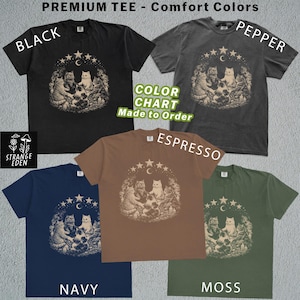 K&ouml;nnte beinhalten: F&uuml;nf kurz&auml;rmelige T-Shirts in den Farben Schwarz, Pfeffer, Espresso, Marineblau und Moos. Jedes T-Shirt zeigt eine Grafik von Katzen, die in einem Kreis unter einer Mondsichel und Sternen sitzen. Text umfasst PREMIUM TEE, Comfort Colors und STRANGE EDEN.