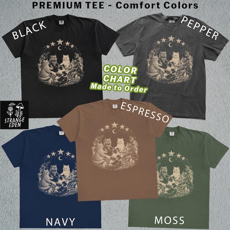 K&ouml;nnte beinhalten: F&uuml;nf kurz&auml;rmelige T-Shirts in den Farben Schwarz, Pfeffer, Espresso, Marineblau und Moos. Jedes T-Shirt zeigt eine Grafik von Katzen, die in einem Kreis unter einer Mondsichel und Sternen sitzen. Text umfasst PREMIUM TEE, Comfort Colors und STRANGE EDEN.