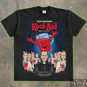 May include: Black t-shirt featuring a graphic of a red Kool-Aid pitcher with a smiling face. The text "STEVE BUSCEMI Kool-Aid BASED ON A TRUE STORY" is printed above the pitcher. The text "A PICTURE BY MARTIN SCORSESE CONTINENTAL STUDIOS" is printed below the pitcher. There are several people in the background.