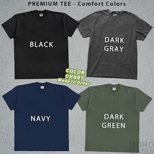 May include: A color chart featuring four t-shirts in black, dark gray, navy, and dark green. Each shirt displays its color name in white text. The top of the image reads "PREMIUM TEE - Comfort Colors". A green sticker says "COLOR CHART Made to Order".
