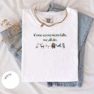 May include: White t-shirt with the text "if one ecosystem falls, we all do." and a row of watercolor animal illustrations including an owl, moose, polar bear, bear, whale, and wolf.