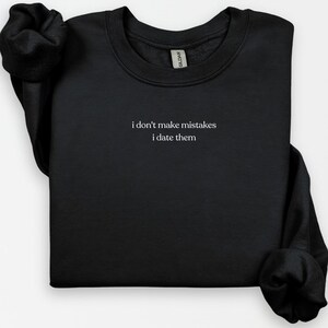 Puede incluir: Sudadera negra con el texto "i don't make mistakes i date them" impreso en blanco.