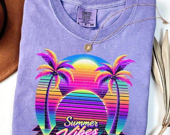 Può includere: T-shirt viola con grafica retrò di un tramonto, palme e la scritta "Summer Vibes". La maglietta ha girocollo e maniche corte. Una collana d'oro è drappeggiata sulla maglietta. La maglietta è realizzata in materiale morbido.