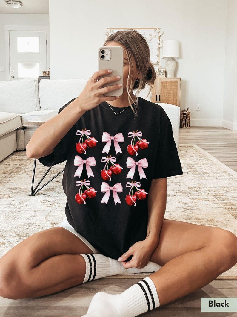 May include: Black t-shirt with a graphic print of red cherries with pink bows.