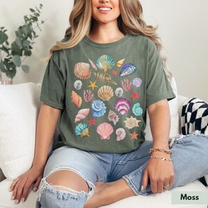 Op de afbeelding: Een groen T-shirt met een kleurrijke schelp print. Het shirt heeft een losse pasvorm en korte mouwen.
