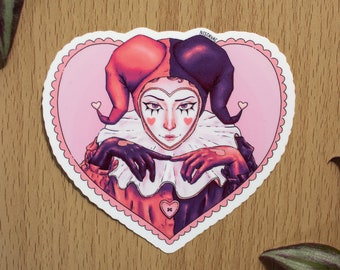 May include: A sticker of a jester with a red and black jester hat, wearing a white ruff, and holding their hands together in front of their chest. The jester is inside a pink heart with a white outline and a scalloped edge. The sticker has the text "NISAVAC" in the top right corner.
