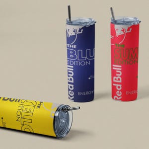 May include: Three insulated tumblers with straws, featuring the Red Bull logo and text. One is yellow with "THE YELLO EDITION", another is blue with "THE BLU EDITION", and the third is red with "THE SUM EDITION".