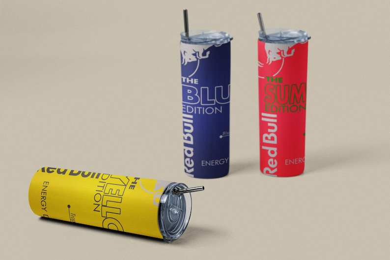May include: Three insulated tumblers with straws, featuring the Red Bull logo and text. One is yellow with "THE YELLO EDITION", another is blue with "THE BLU EDITION", and the third is red with "THE SUM EDITION".