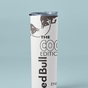 May include: White insulated tumbler with a black lid. The tumbler features the Red Bull logo and the text "THE COCO EDITION". The design includes a bull graphic.