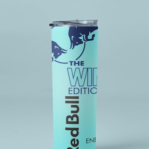 May include: A tall, light blue tumbler with a dark blue lid. The tumbler features the Red Bull logo and the text "THE WINTER EDITION". The design includes dark blue bull silhouettes. A sleek, modern beverage container.