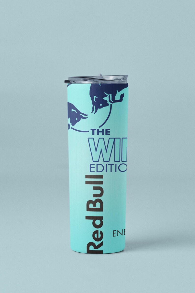May include: A tall, light blue tumbler with a dark blue lid. The tumbler features the Red Bull logo and the text "THE WINTER EDITION". The design includes dark blue bull silhouettes. A sleek, modern beverage container.