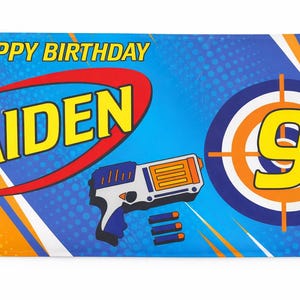 May include: A banner with the text "HAPPY BIRTHDAY AIDEN 9" in yellow and red. The banner features a toy gun and a target with the number 9. The background is blue and orange.