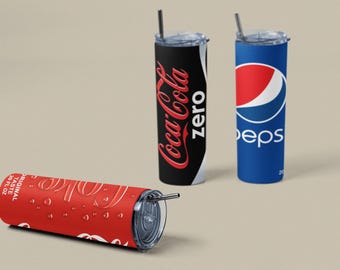 May include: Tumblers featuring Coca-Cola Zero, Pepsi, and a Coca-Cola design. The Coca-Cola Zero tumbler is black with red text. The Pepsi tumbler is blue with a red and white logo. The red Coca-Cola tumbler is lying down.